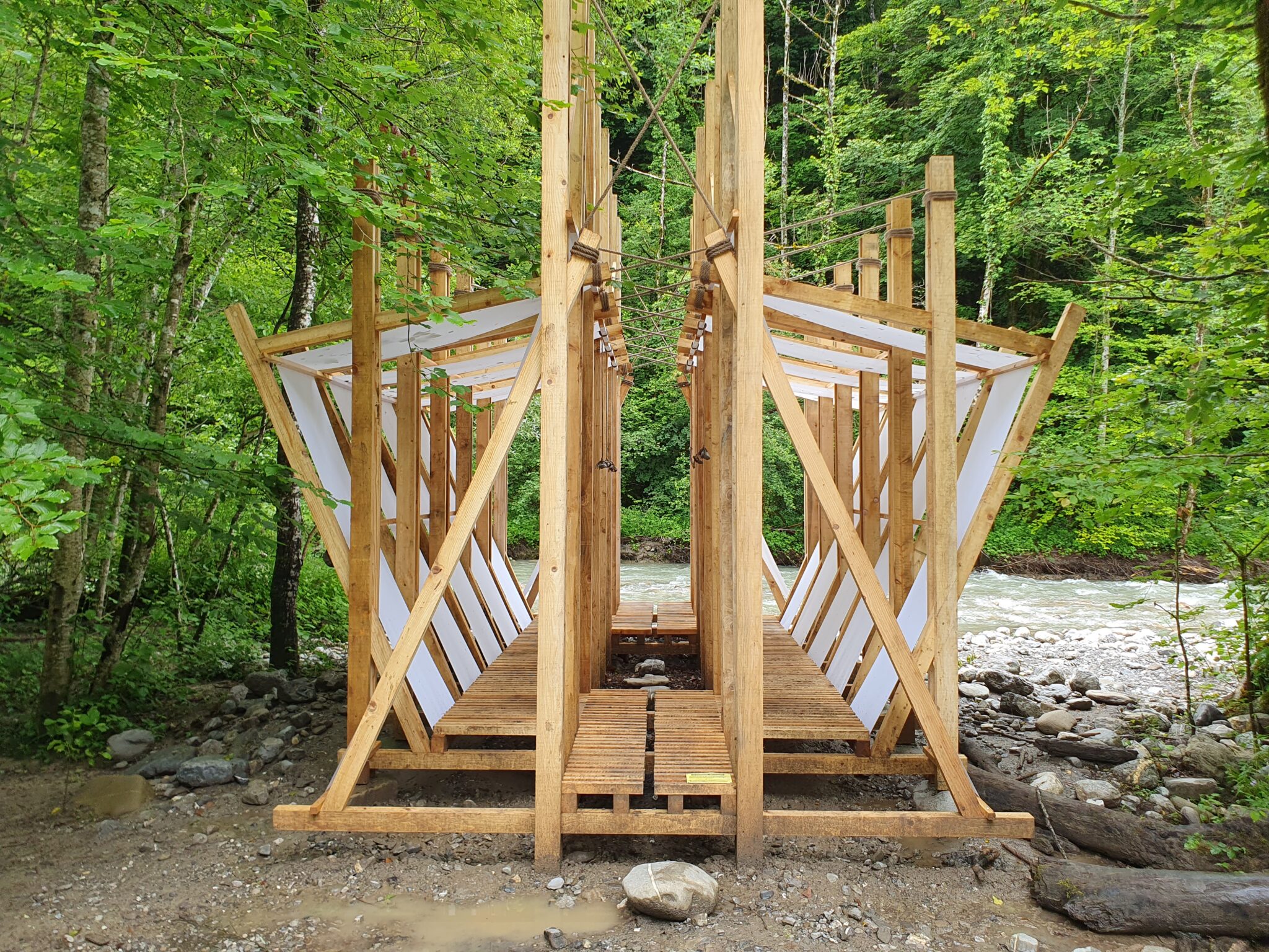 Cabane Saint-Ferréol bois et toiles au bord de la rivière sous les arbres