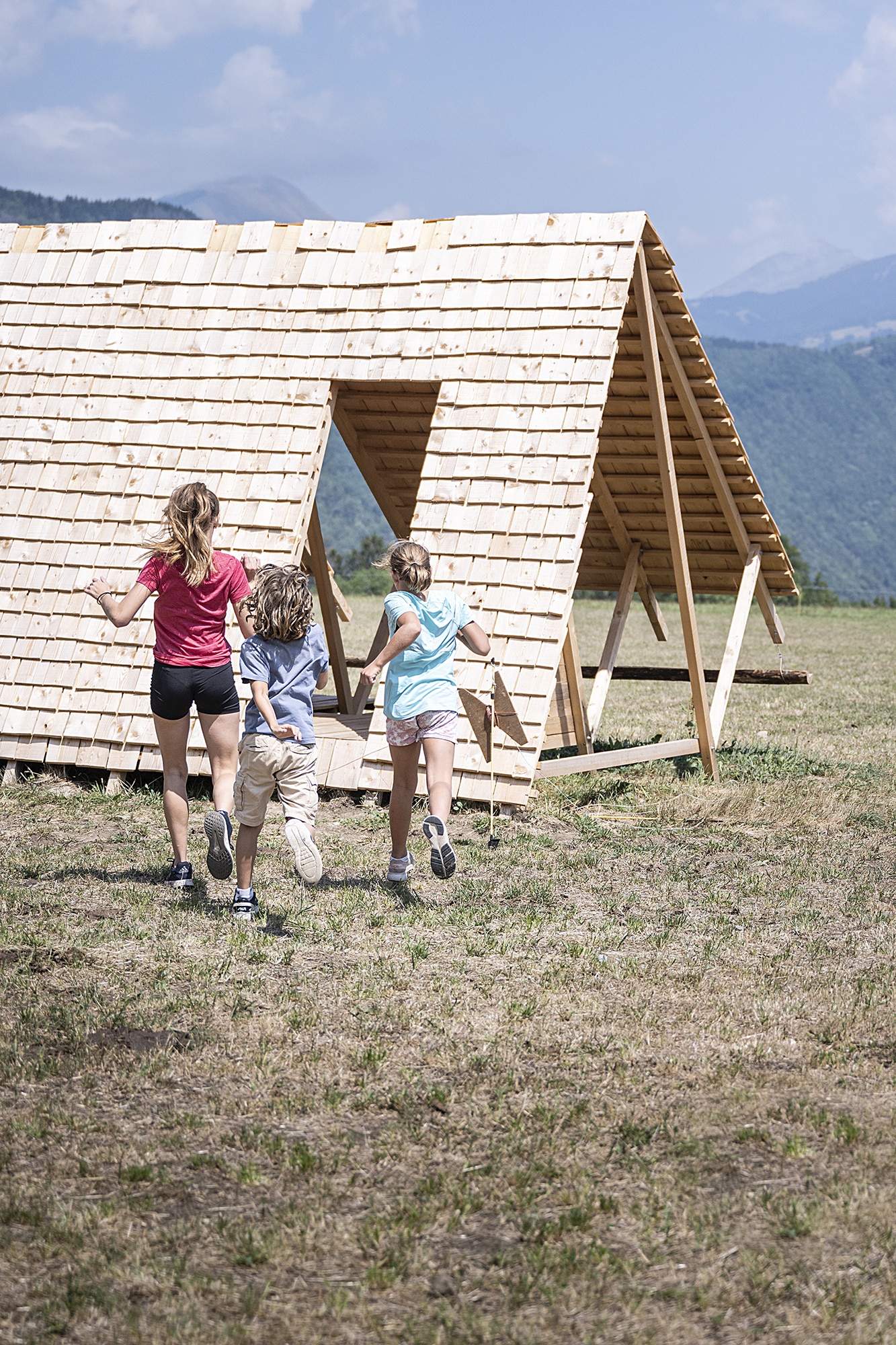 3 enfants courant vers une cabane du Festival des cabanes