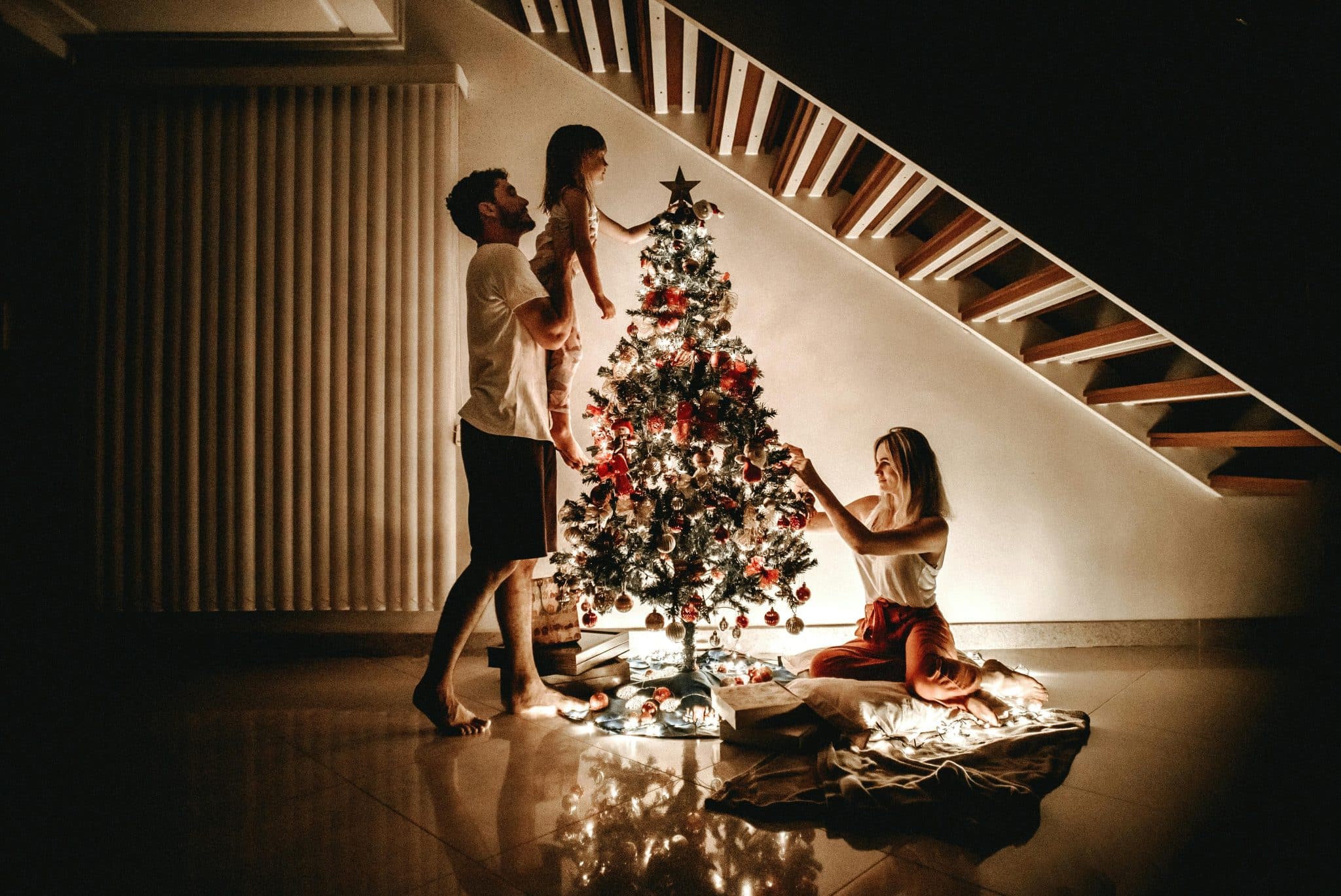 un homme, une femme et leur fille décorant un sapin de Noël